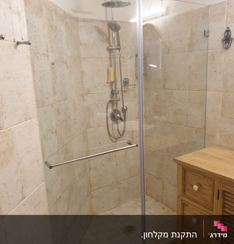 מקלחת עם דלת זכוכית, ראש מקלחת ומדף סבון